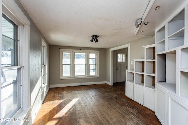 interior space featuring a textured ceiling, dark wood-style flooring, and baseboards