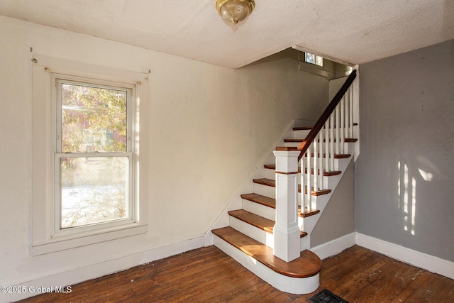 staircase with hardwood / wood-style flooring, baseboards, and a textured ceiling