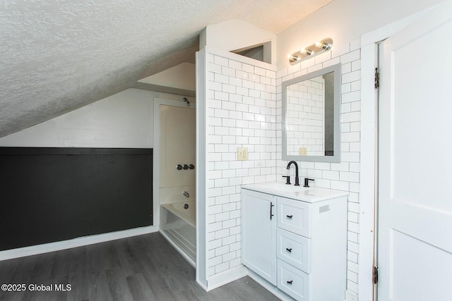 bathroom featuring vaulted ceiling, a textured ceiling, vanity, and wood finished floors