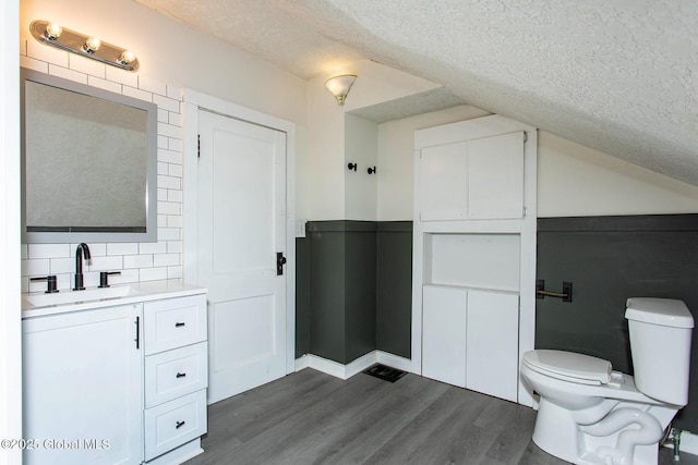 bathroom featuring decorative backsplash, toilet, wood finished floors, a textured ceiling, and vanity