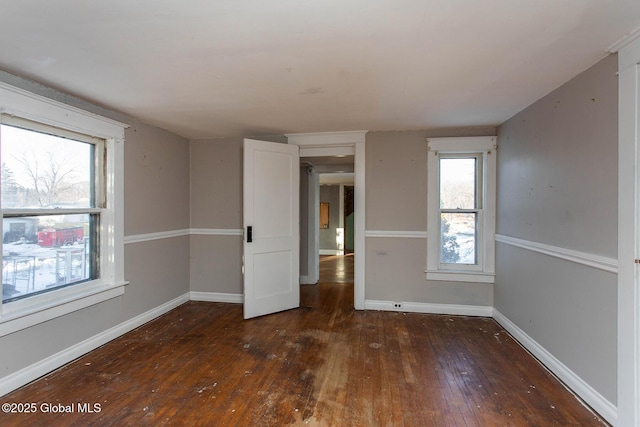 spare room with baseboards and hardwood / wood-style floors