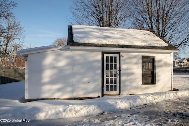 snow covered structure featuring an outbuilding