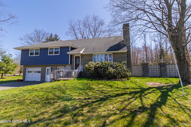 tri-level home featuring driveway, a chimney, roof with shingles, an attached garage, and a front lawn