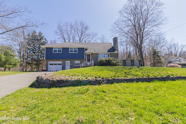 split level home featuring a garage, a front yard, driveway, and a chimney