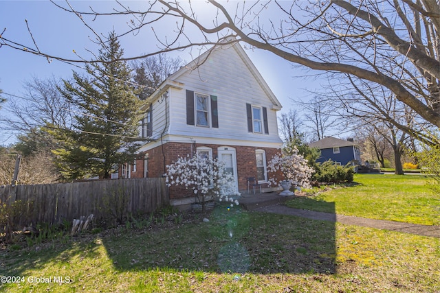 view of front of house with fence, a front lawn, and brick siding