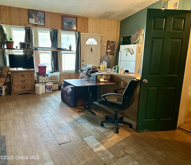 office space with wooden walls, wood finished floors, and a textured ceiling