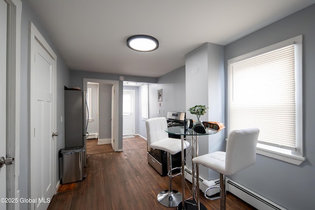 dining area featuring a baseboard radiator, a healthy amount of sunlight, dark wood finished floors, and baseboards