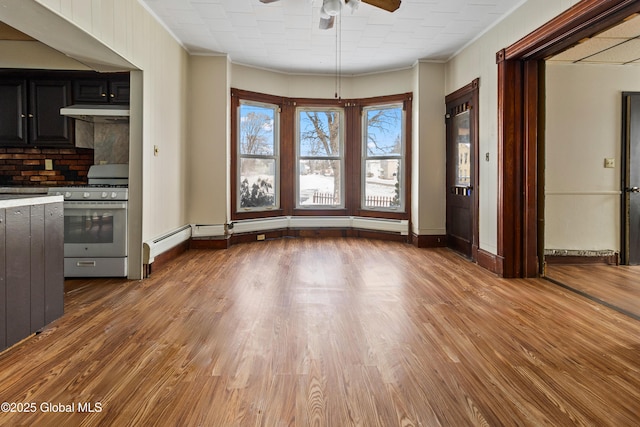 unfurnished dining area featuring baseboards, ceiling fan, ornamental molding, and wood finished floors