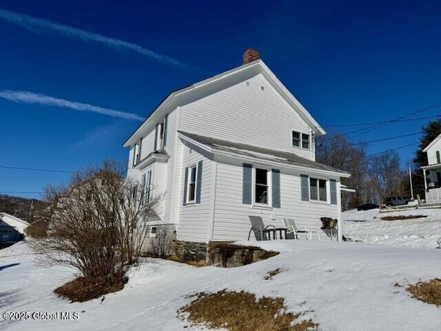 snow covered property with a chimney