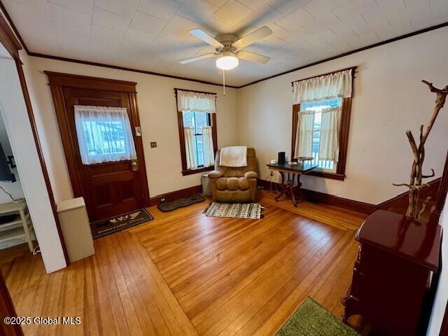 interior space featuring light wood-style floors, crown molding, and baseboards