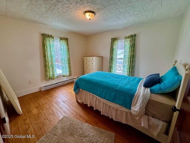 bedroom featuring wood-type flooring, baseboards, and baseboard heating