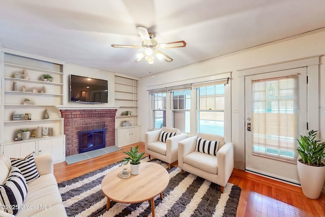 living room with a ceiling fan, light wood-type flooring, a fireplace, and plenty of natural light