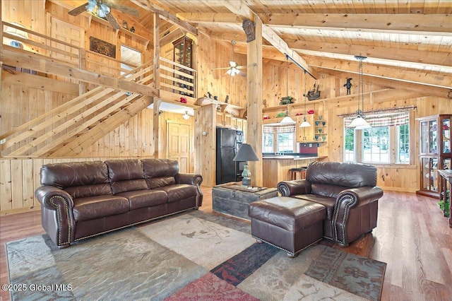 living area with wood walls, ceiling fan, and wood finished floors