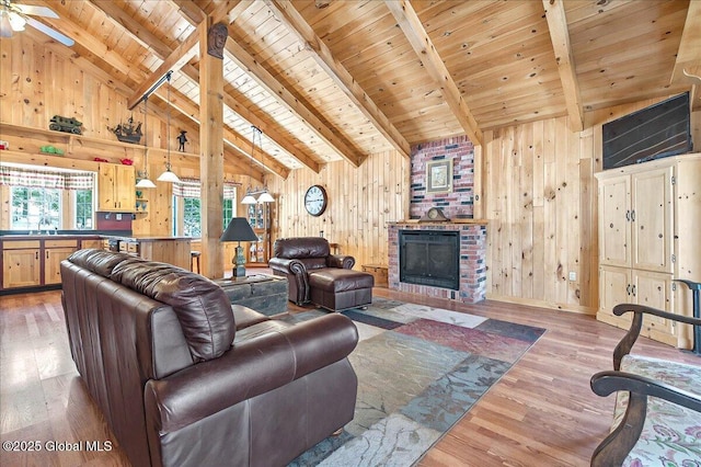 living area featuring beam ceiling, wood finished floors, wood ceiling, and wood walls