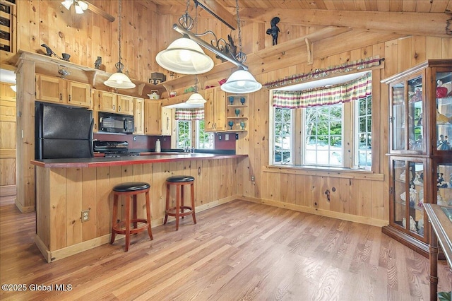 kitchen featuring black appliances, vaulted ceiling with beams, plenty of natural light, and light wood finished floors