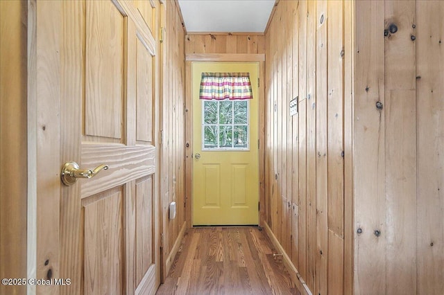 entryway with baseboards, wood finished floors, and wood walls