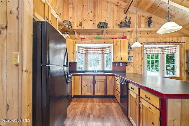 kitchen featuring light wood finished floors, lofted ceiling with beams, a peninsula, black appliances, and a sink