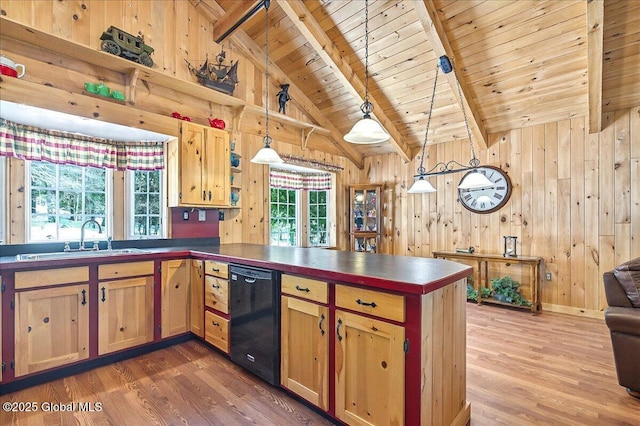 kitchen featuring a sink, dishwasher, a peninsula, and wood walls