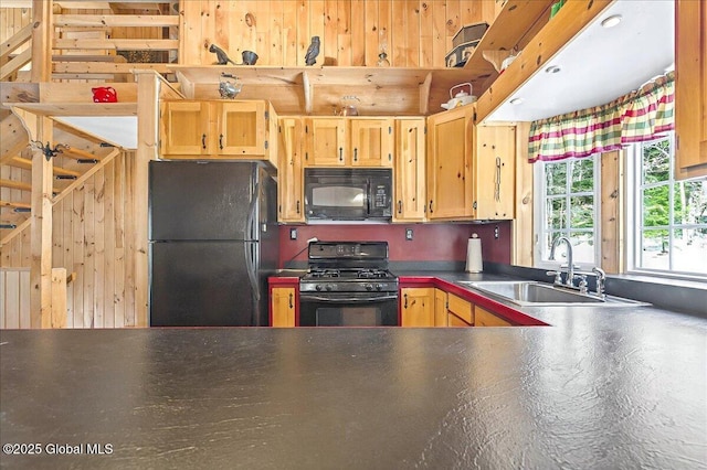 kitchen featuring black appliances, dark countertops, and a sink