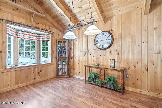 interior space featuring wooden walls, wood finished floors, baseboards, lofted ceiling with beams, and wooden ceiling