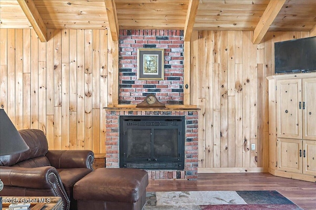 living room featuring beam ceiling, wood finished floors, wooden walls, wooden ceiling, and a fireplace