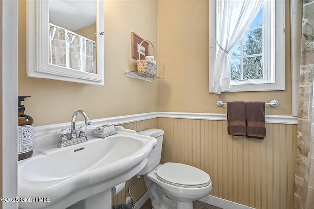 bathroom with wainscoting, toilet, and a sink