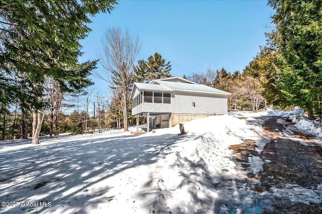 snow covered rear of property with a sunroom