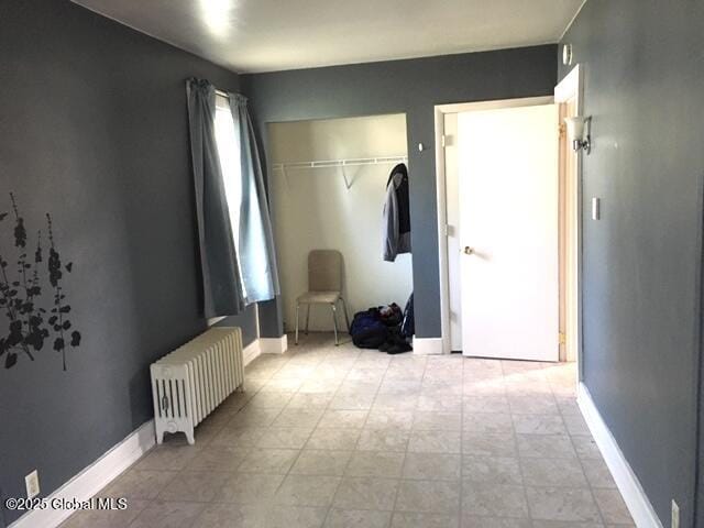 bedroom with baseboards, a closet, and radiator