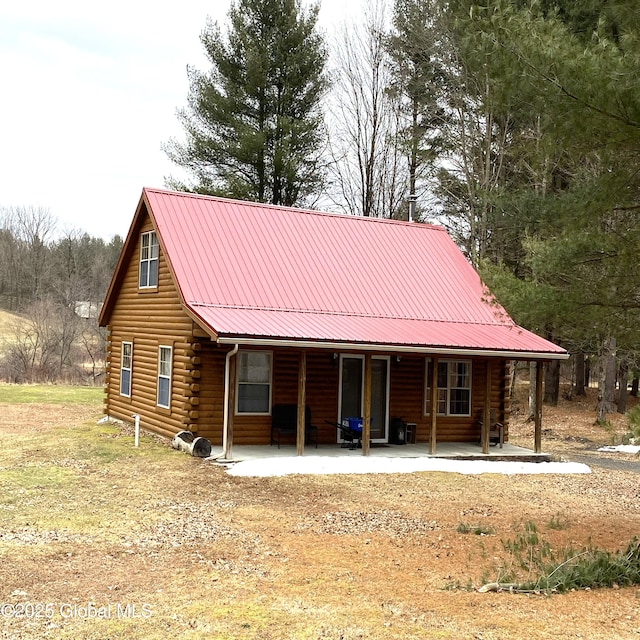 rear view of house featuring covered porch, log exterior, and metal roof