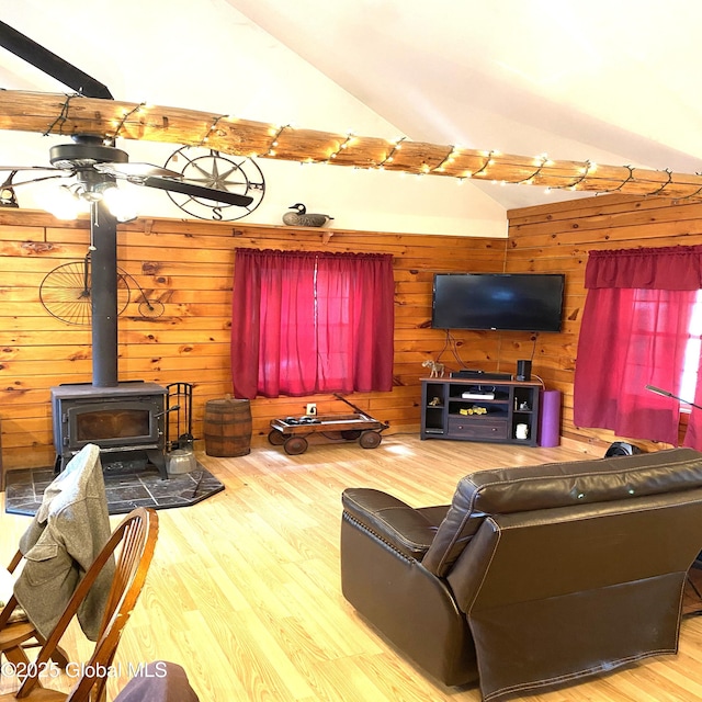 living area with vaulted ceiling, wood walls, wood finished floors, and a wood stove