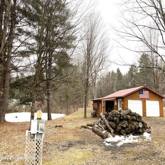 view of side of property with a detached garage, metal roof, and an outdoor structure