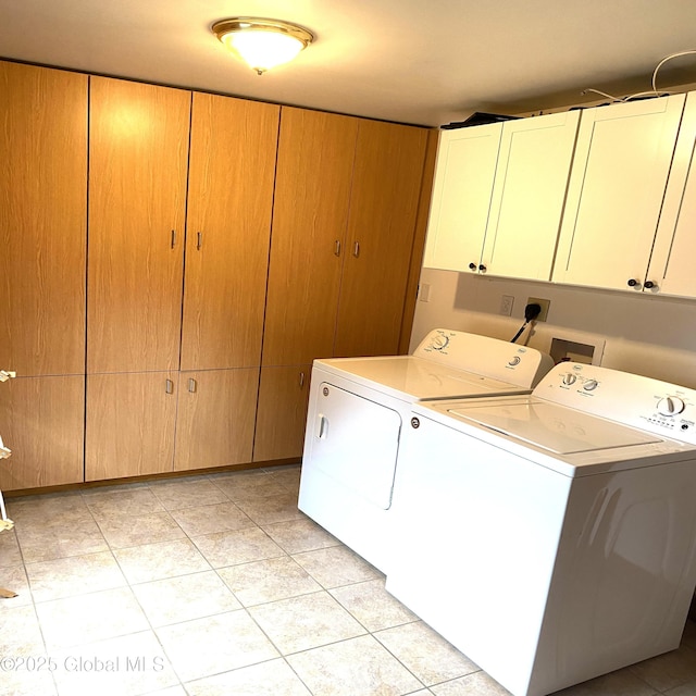 clothes washing area with light tile patterned flooring, washing machine and dryer, and cabinet space