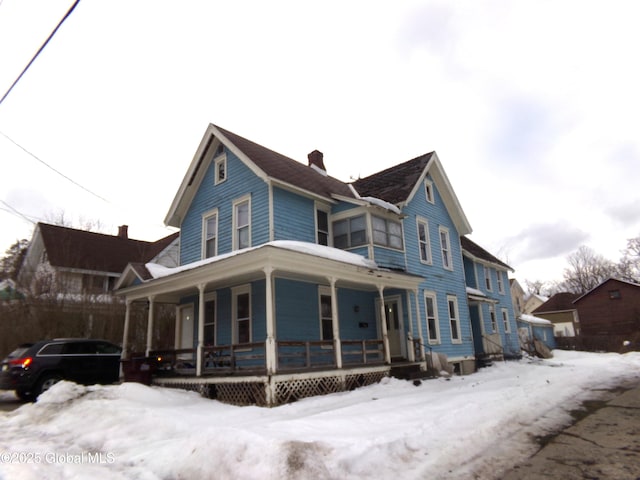 view of front facade featuring covered porch and a chimney