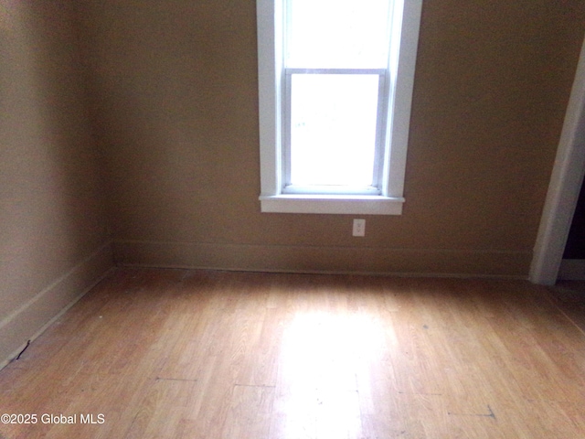 unfurnished room with baseboards and light wood-style flooring