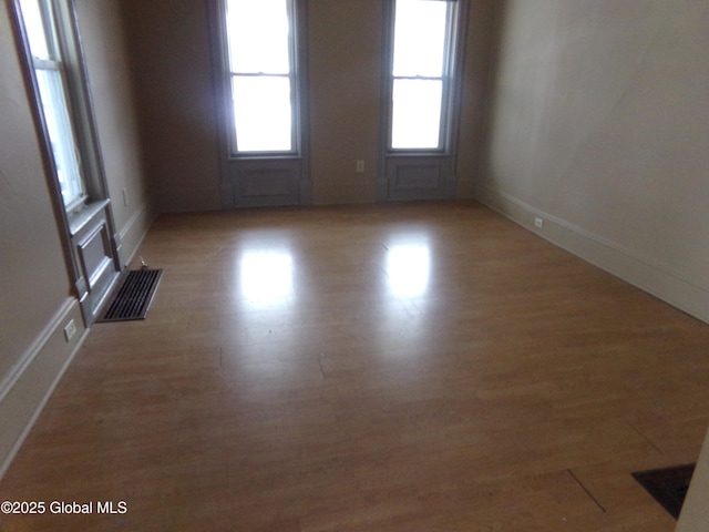 spare room with light wood-style flooring, baseboards, and visible vents