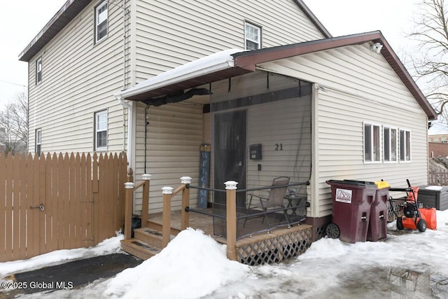 snow covered house with fence and a wooden deck