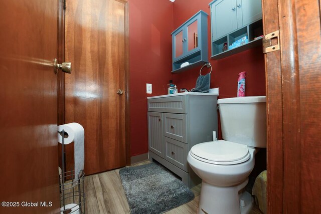 half bath with wood finished floors, vanity, and toilet