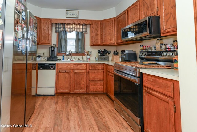 kitchen with brown cabinets, light wood-style floors, stainless steel appliances, and light countertops