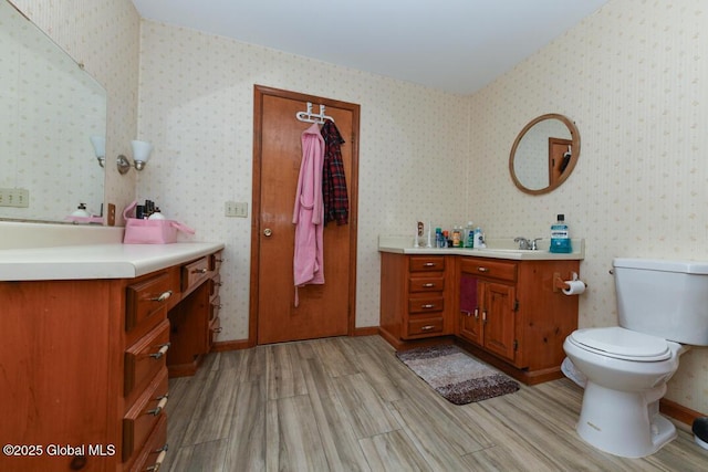 bathroom with wood finished floors, vanity, toilet, and wallpapered walls