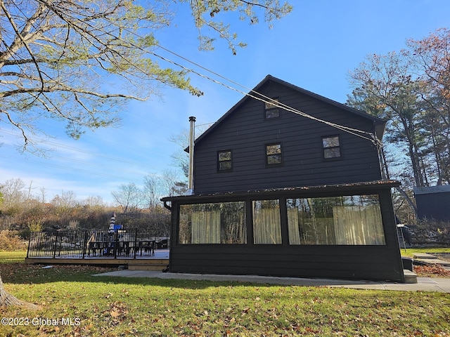 view of home's exterior with a sunroom, a yard, and a deck