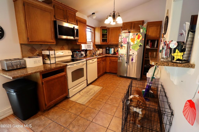 kitchen with a sink, vaulted ceiling, appliances with stainless steel finishes, brown cabinets, and pendant lighting