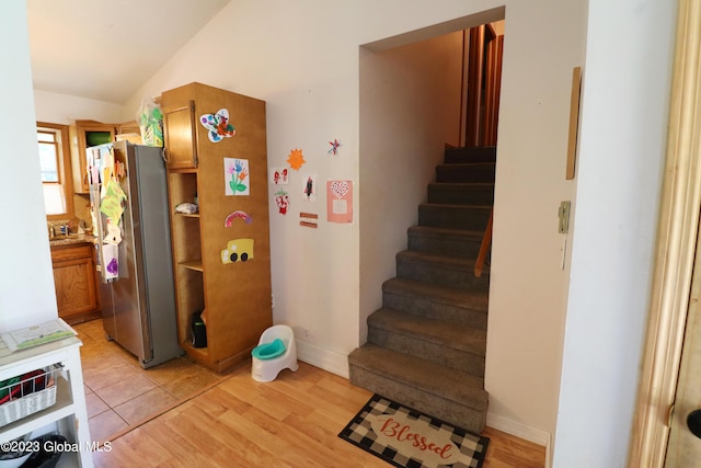 stairway featuring lofted ceiling, wood finished floors, and baseboards