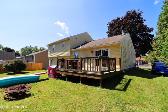 rear view of house with a fire pit, a yard, fence, and a wooden deck