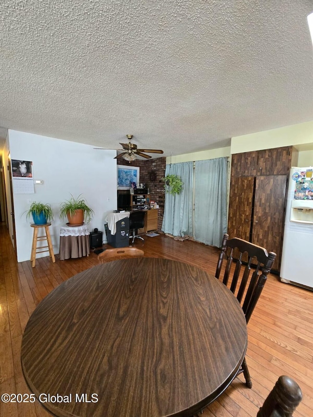 dining area featuring a ceiling fan, wood-type flooring, and a textured ceiling