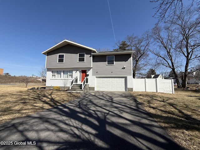 view of front of house featuring aphalt driveway, a gate, an attached garage, and fence