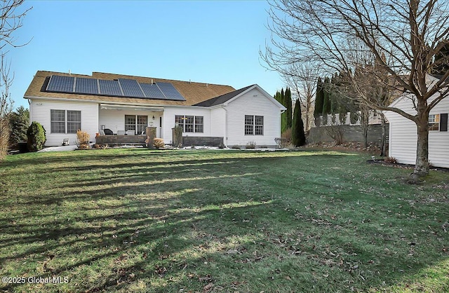 back of property with a yard and roof mounted solar panels