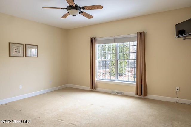 empty room featuring visible vents, light carpet, baseboards, and ceiling fan