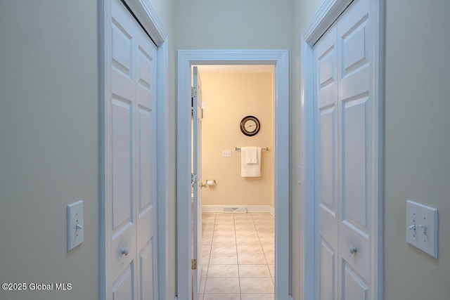 hallway with light tile patterned floors, visible vents, and baseboards