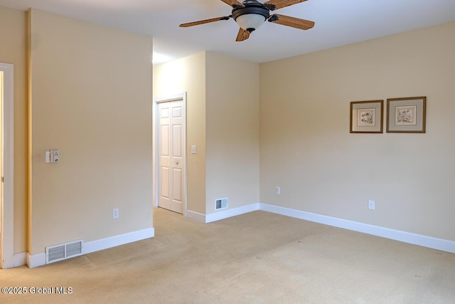 empty room with ceiling fan, light colored carpet, visible vents, and baseboards