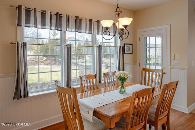 dining space with a wainscoted wall, plenty of natural light, and light wood-style flooring